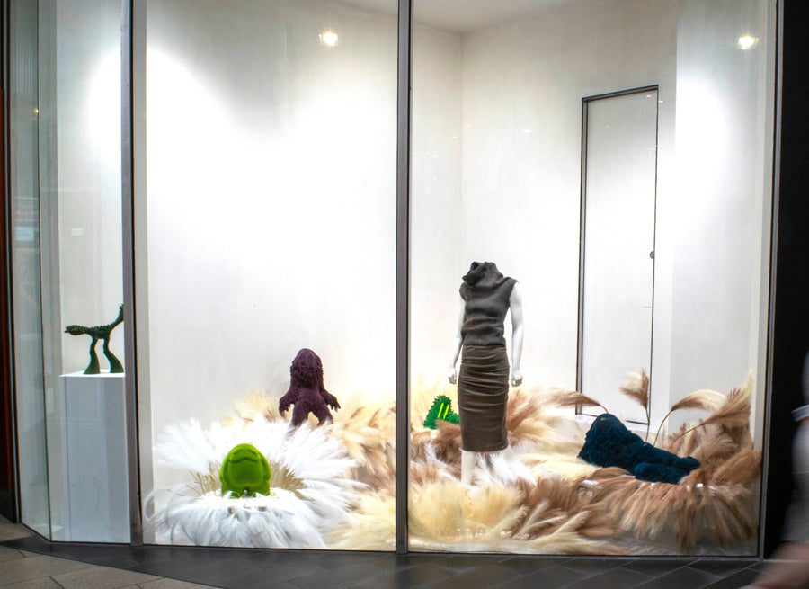 Brad Gunn window display with a mannequin, feathery grasses and sculptural figures