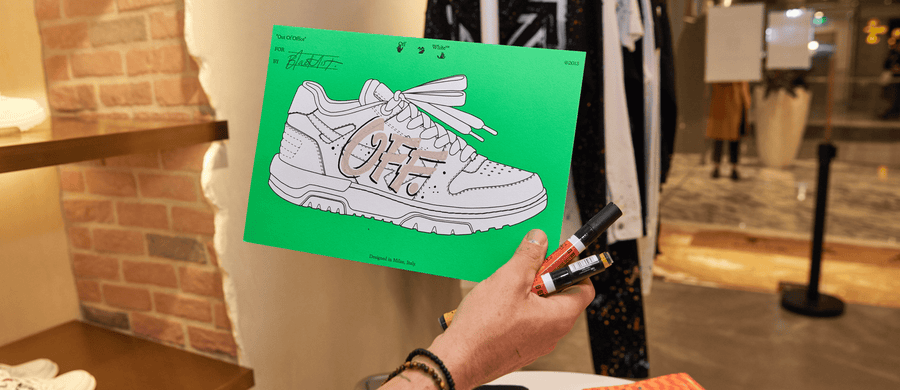 Hand customising an Off-White Out Of Office sneaker drawing inside an Off-White boutique