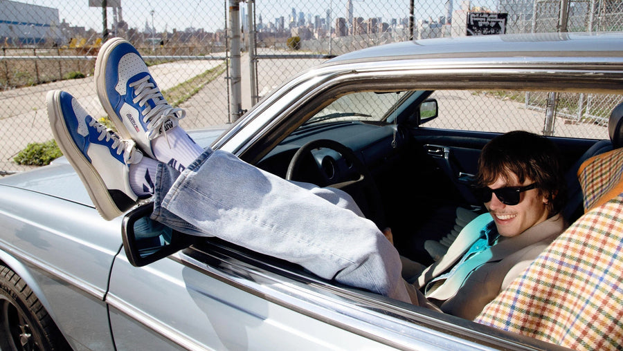 Autry campaign: a man reclining in a car with his blue and white sneakers out the window